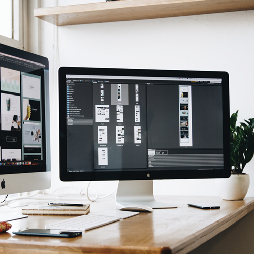 2 ordinateurs MAC posés sur un bureau, montrant des dossiers avec des images.