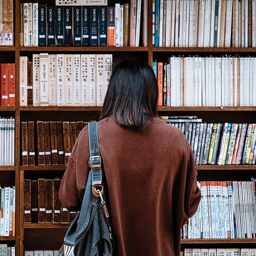 Personne de dos devant une bibliothèque avec le logo de Sciences Po