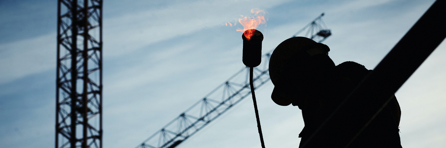 Personne sur un chantier devant une grue et avec du feu dans les mains