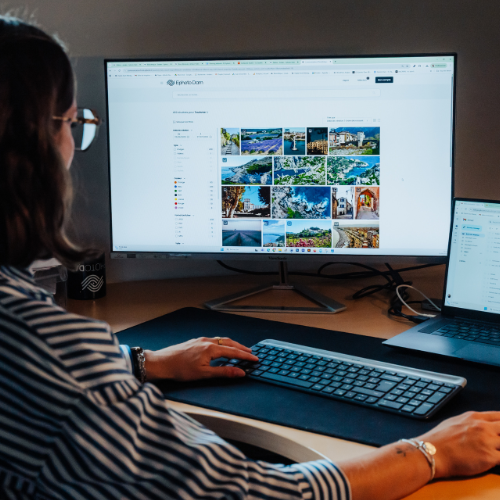 Personne qui travaille sur un bureau qui regarde deux écrans en face d'elle.