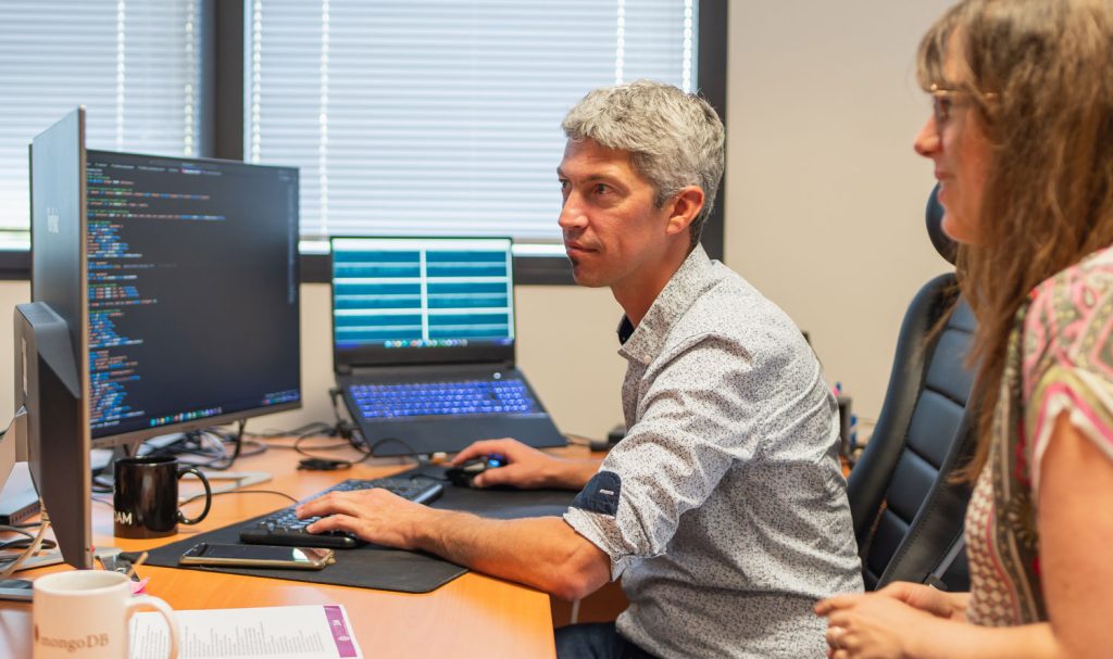 2 personnes assises à un bureau regardant un écran