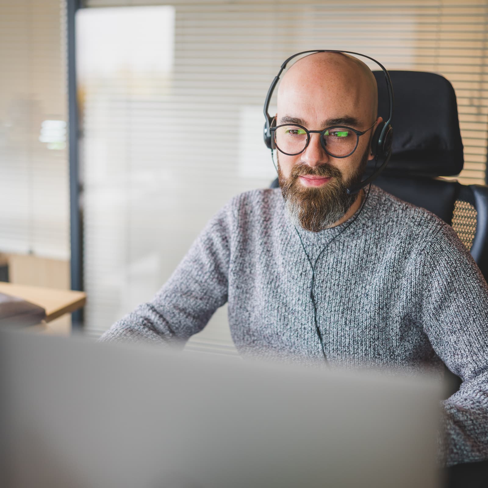 Homme barbu avec lunettes travaillant sur un ordinateur, illustrant la gestion avancée des actifs numériques avec Ephoto Dam.