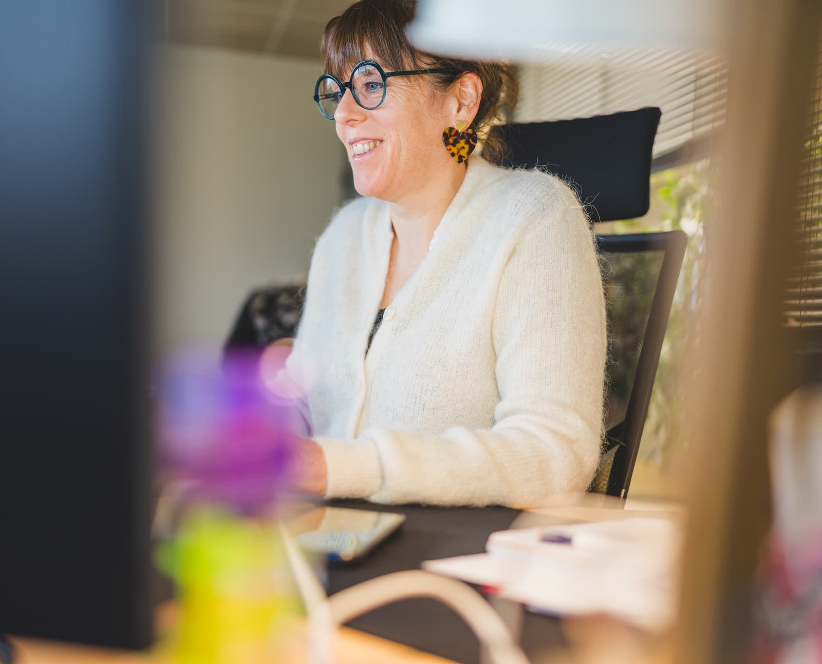 Femme souriante travaillant sur un ordinateur, illustrant l'accompagnement à l'apprentissage des fonctionnalités du logiciel de gestion de photothèque Ephoto Dam.