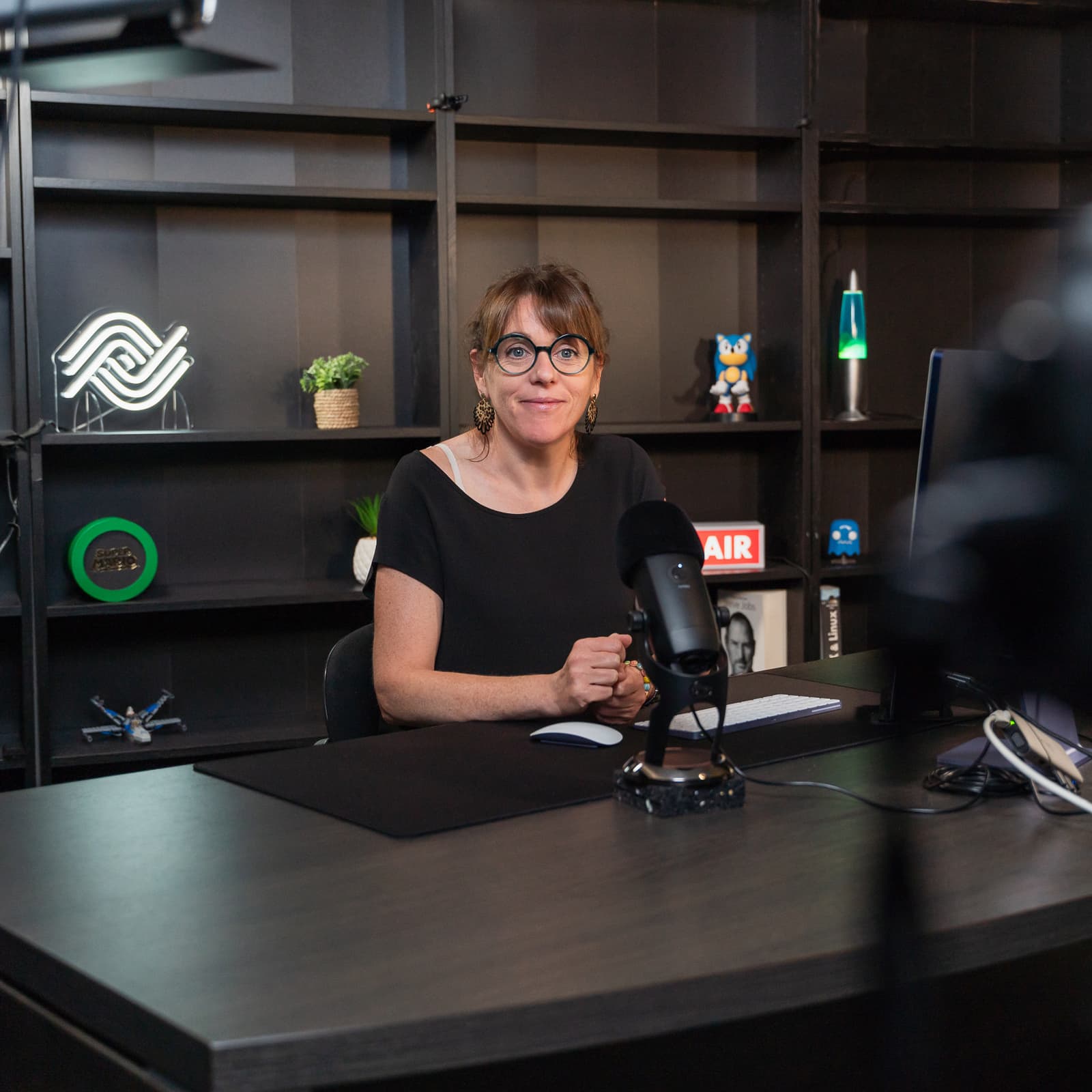 Femme assise souriant à une caméra en train de la filmer dans un studio de tournage vidéo professionnel pour la solution photothèque Ephoto Dam.
