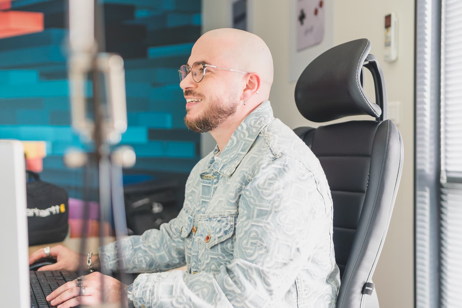 Homme à lunette souriant travaillant sur ordinateur, effectuant une reprise de données pour faciliter la transition de médias vers le logiciel de Digital Asset Management Ephoto Dam.