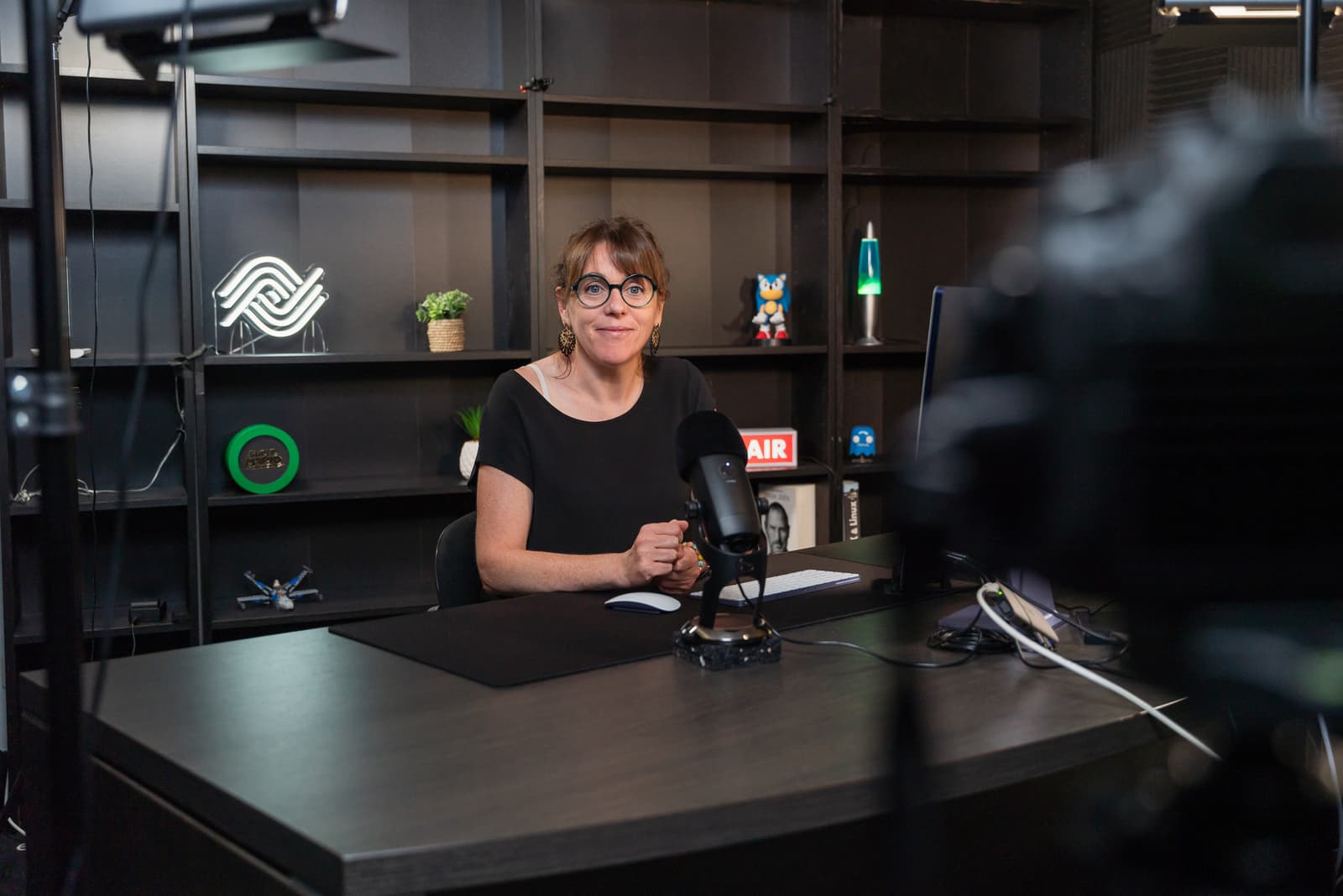 Femme assise souriant à une caméra en train de la filmer dans un studio de tournage vidéo professionnel pour la solution photothèque Ephoto Dam.