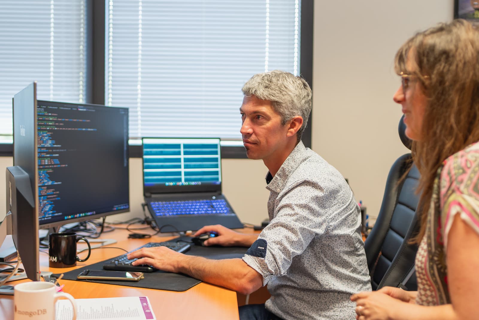 Un homme et une femme en train de regarder un écran d'ordinateur avec du code HTML.