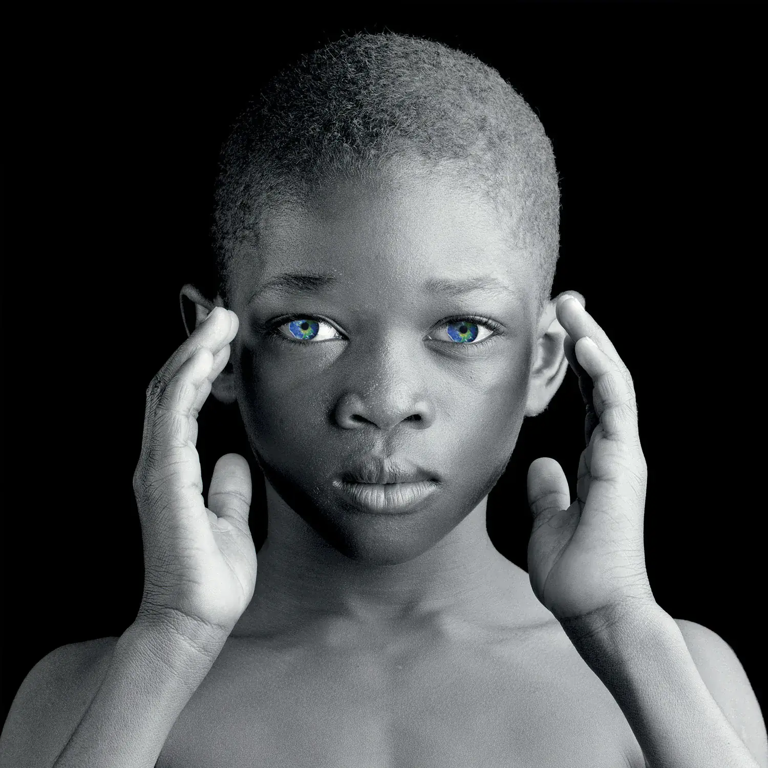 Portrait en noir et blanc d'un enfant mettant ses deux mains au bord de son visage.